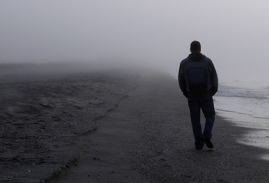 En mørk strand med en gående person