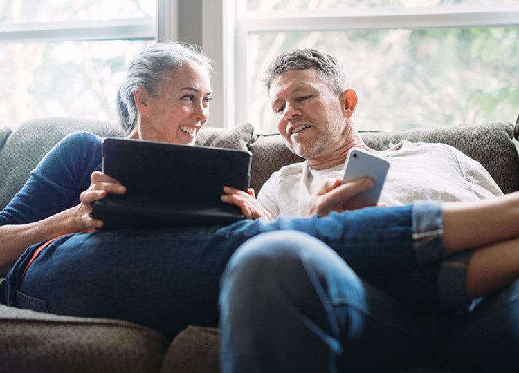 Par ligge i en sofa og kigger på tablet