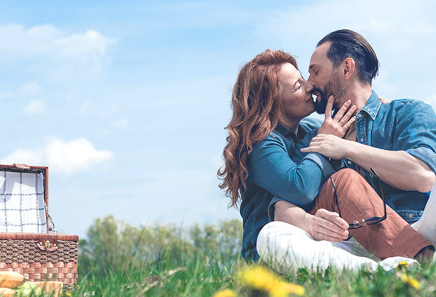 Kyssende par på picnic-tur på en græsplæne